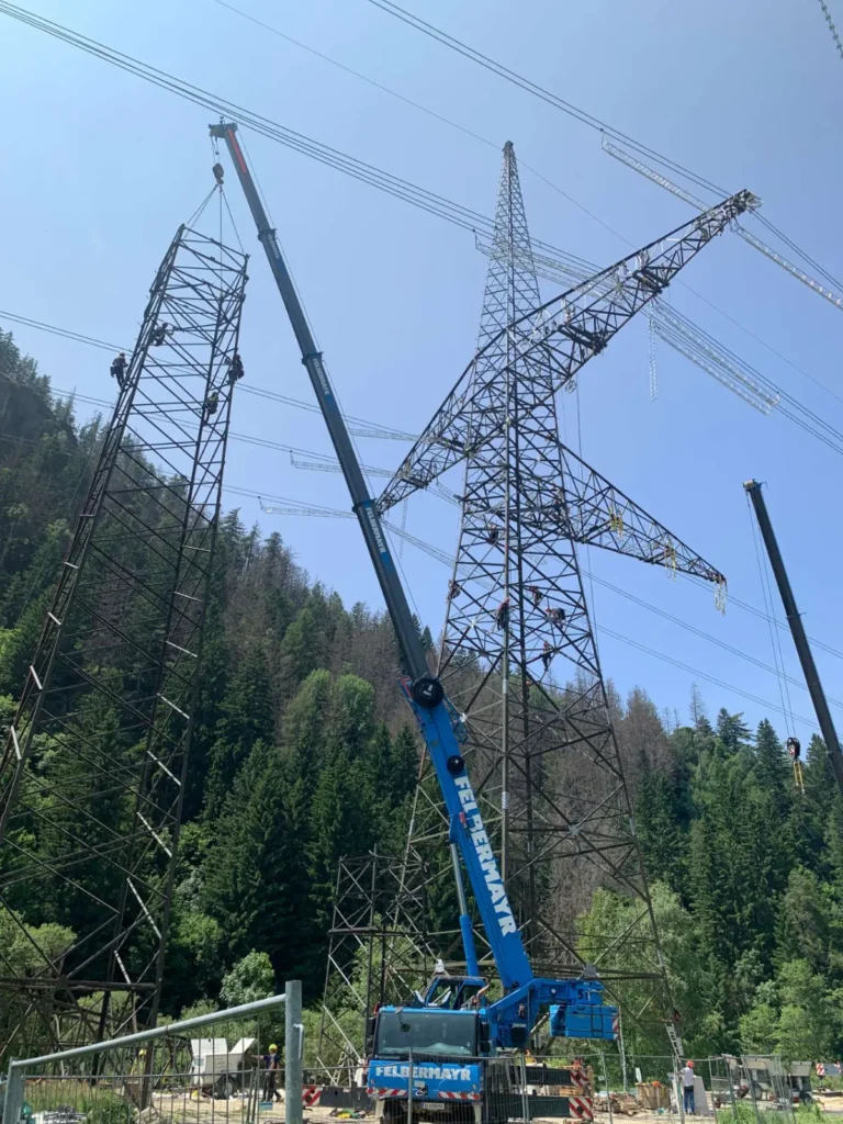 Ein Autokran hebt die tonnenschweren Stahlgitterteile, die die Manda von C-Team in schwindelerregender Höhe verschrauben