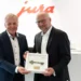 Passend zur Eröffnung in Linz überreichte Jura Österreich-Geschäftsführer Andreas Hechenblaikner – stellvertretend für Jura-CEO Emanuel Probst – symbolisch den „Schlüssel des Erfolges“ an SCD-Eigentümer Franz Holzbauer. © SCD
